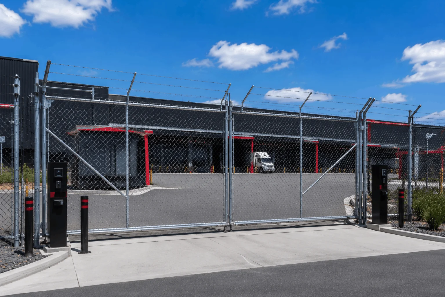 Double chainwire gate with 3 barb security fencing at industrial facility.